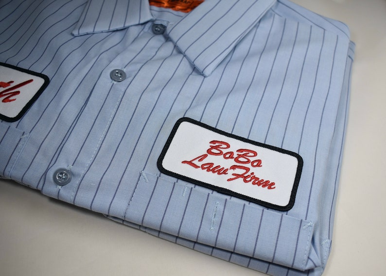 May include: A blue and white striped work shirt with a white patch that says "Bobo Law Firm" in red cursive lettering.