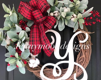May include: A Christmas wreath with a red and black plaid bow, white cotton sprigs, and red berries. The wreath is decorated with a white wooden letter Y.