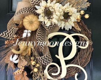 May include: A fall-themed wreath with a burlap bow, sunflowers, cotton bolls, and a wooden letter "P".