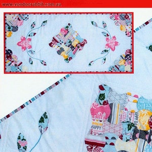 May include: A white table runner with a blue and pink floral design. The runner features a patchwork design in the center with words like "Happy" and "Joy". The runner is 15 inches by 33 inches.
