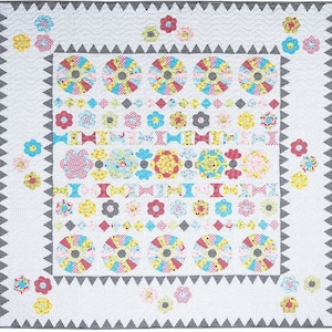 May include: A white quilt with a black and white geometric border. The quilt features a variety of colorful patchwork designs, including flowers, circles, and squares.