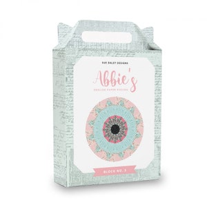 May include: A light blue box with a white label that says "Sue Daley Designs Abbie's English Paper Piecing Block No. 5". The label also features a pink and blue mandala design.