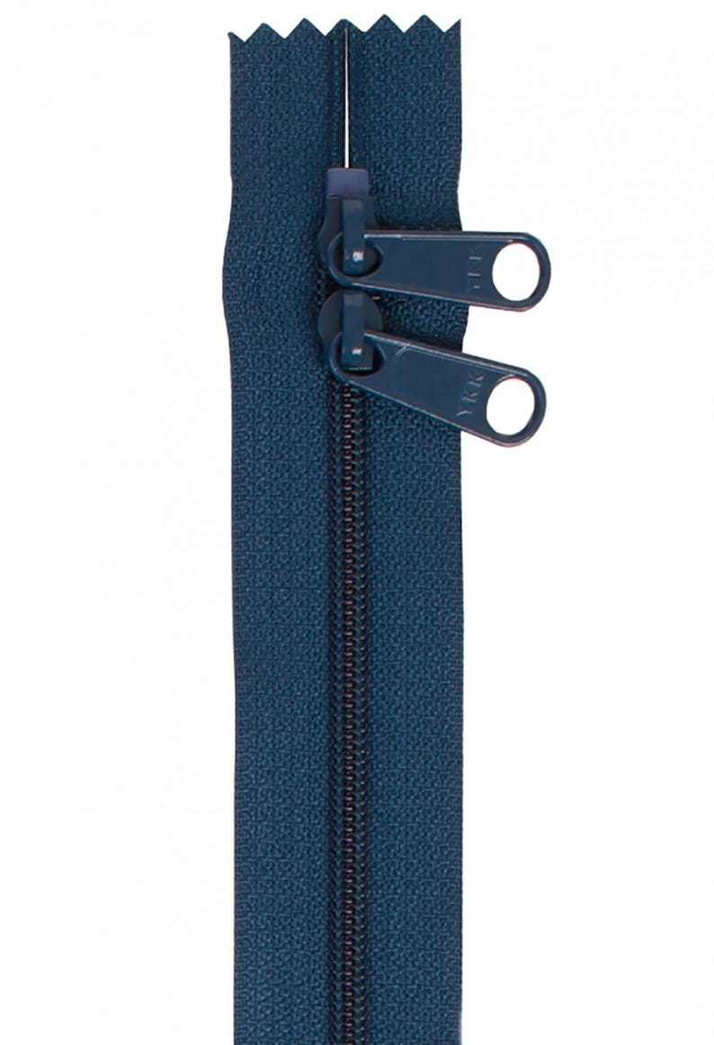 May include: A dark blue zipper with two pull tabs. The zipper is closed and the pull tabs are in the up position.