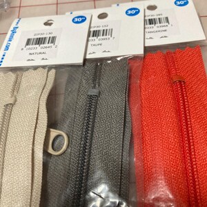 May include: Three 30-inch zipper tapes in natural, taupe, and tangerine colors. The zipper tapes are packaged in clear plastic bags with labels that include the product number, color, and size.
