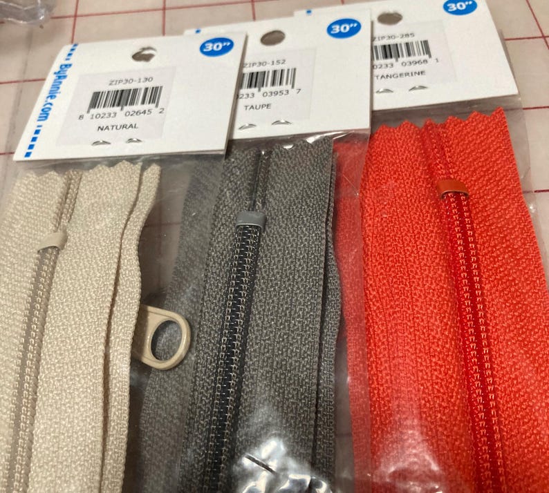 May include: Three 30-inch zipper tapes in natural, taupe, and tangerine colors. The zipper tapes are packaged in clear plastic bags with labels that include the product number, color, and size.