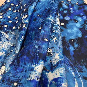 May include: Blue and white abstract printed fabric with a white border. The fabric has a textured, brushstroke-like pattern.