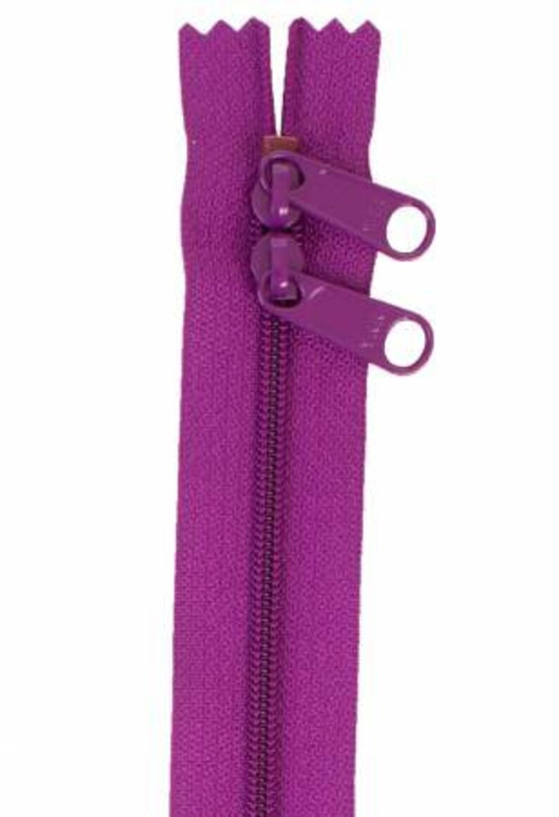May include: A purple zipper with two metal sliders. The zipper is closed and ready to be sewn into a garment.