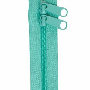 May include: A turquoise zipper with two pull tabs. The zipper is closed and ready to be sewn into a garment or project.