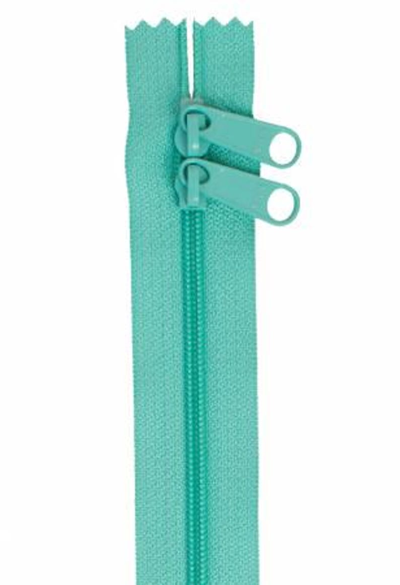 May include: A turquoise zipper with two pull tabs. The zipper is closed and ready to be sewn into a garment or project.