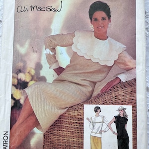 以下が含まれることがあります： ストライプのドレスを着た女性が特徴のSimplicityの縫製パターン。フリルカラー付き。パターンには署名と他の衣服デザインのイラストが含まれています。パターンは番号6042でラベル付けされています。