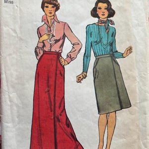 May include: Vintage Simplicity sewing pattern number 6369 for a skirt. The pattern is for size 14 with a 28 inch waist. The pattern shows two women wearing different versions of the skirt. One woman is wearing a red skirt with a long, flowing hemline. The other woman is wearing a green skirt with a shorter hemline.
