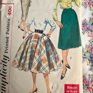 May include: A Simplicity 2654 sewing pattern envelope featuring illustrations of three skirt styles: a herringbone pencil skirt, a solid green A-line skirt, and a plaid full skirt. The text includes Waist 30, Hip 40, 40c, and Simple to make.