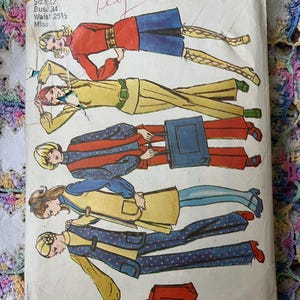 May include: A vintage Simplicity 9611 sewing pattern envelope featuring illustrations of five different outfits including tunics, vests, and trousers. The paper envelope shows size 12, bust 34, and waist 25.5 measurements with colorful fashion sketches.