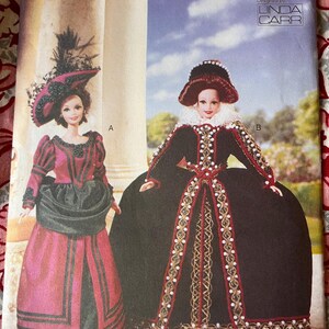 May include: A Vogue Craft pattern featuring two doll designs. One doll wears a pink and black gown with a feathered hat. The other doll is in a black gown with red and gold trim and a matching hat. The pattern is designed by Linda Carr.