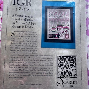 May include: A close-up of a cross-stitch sampler pattern with a colorful design. The sampler is titled "IGR 1749" and is described as a Scottish sampler from the Victoria & Albert Museum in London. The sampler is recommended for intermediate to advanced needleworkers.