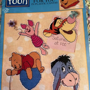 May include: A craft instruction booklet titled Pooh Magnets for You in Plastic Canvas featuring illustrations of Winnie the Pooh, Piglet, Tigger, and Eeyore. The cover displays four finished plastic canvas character magnets on a light peach background.