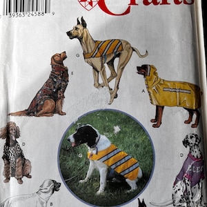 May include: Simplicity Crafts sewing pattern featuring dog clothing designs. The pattern includes illustrations of various dog breeds wearing coats, vests, and raincoats. The pattern is labeled "One Size" and includes the Longia Miller Design logo.