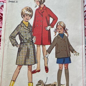 May include: Vintage Simplicity sewing pattern for girls, size 14, breast 32. The pattern features illustrations of three girls wearing coats. The pattern cover is red and white with the Simplicity logo.