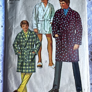 May include: A vintage sewing pattern for a men's robe. The pattern is for sizes 42-44 with a waist size of 38-40. The pattern shows three different styles of robes, one with a plaid pattern, one with a paisley pattern, and one with a solid white color.