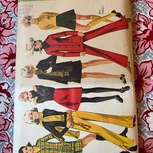 May include: A Simplicity 8409 sewing pattern envelope featuring illustrations of various outfits including a yellow top with shorts, a red suit, a black skirt set, a black top with a red skirt, yellow pants, and a plaid jacket with a mini-pantskirt.