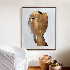 Pode incluir: Pintura abstrata com um design texturizado dourado e marrom sobre fundo branco. A pintura é emoldurada em uma moldura marrom escura.