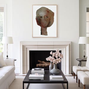 May include: A white room with a fireplace and a painting of a face above it. There is a coffee table in front of the fireplace with a vase of pink flowers on it.