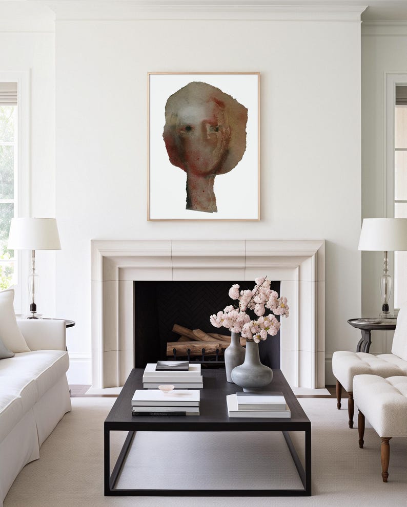 May include: A white room with a fireplace and a painting of a face above it. There is a coffee table in front of the fireplace with a vase of pink flowers on it.