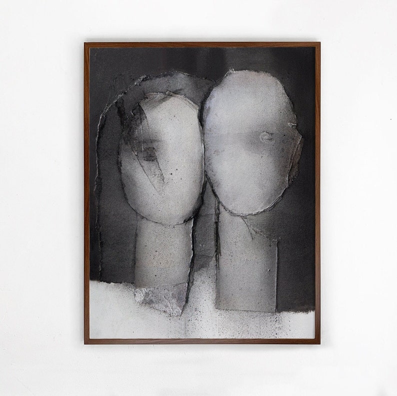 A wood framed art print of a noir abstract portrait of a grayscale love couple on spray-painted black-and-white background. The heads have torn paper layers with exposed grungy edges and two roughly outlined eyes. The texture is rough and grainy.