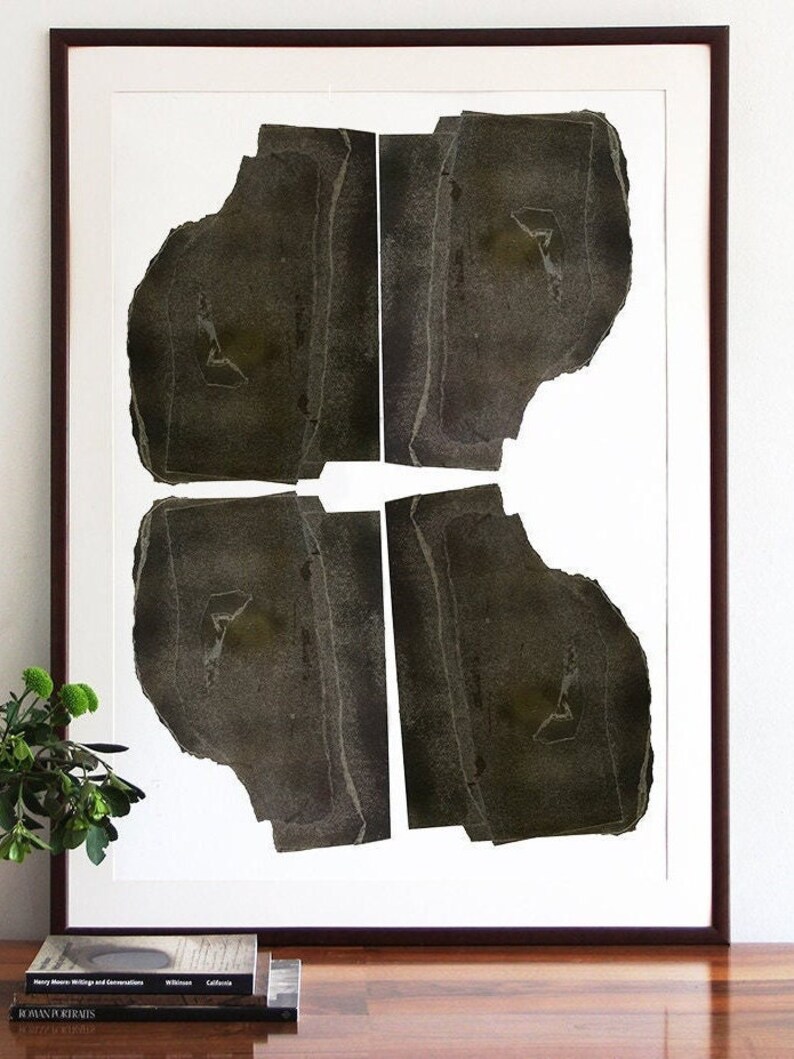 A wall decor with a monochromatic large statement art print of an abstract original portrait with four heads in shades of brushed oil black on a shiny wooden table and some flowers. It has parallel straight torn paper layers for a geometrical feel.