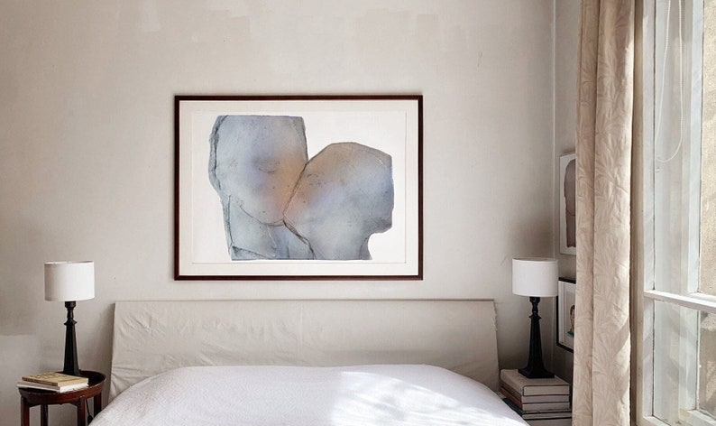 A bedroom wall decor with a dark wood framed high quality art print of a romantic abstract portrait of a love couple kiss in greige, dovetail and silver grey on white. The torn paper have grungy edges and a mural feel. The kiss glows opaque gold.