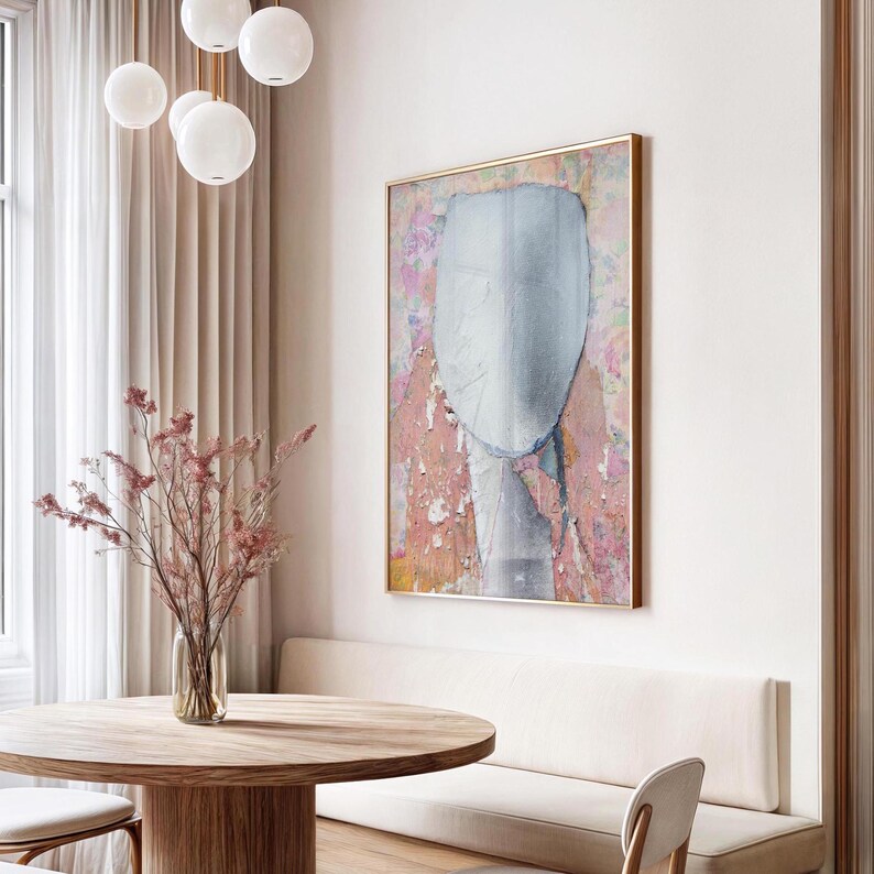 A living room visualization with a framed high quality archival art print of a tender female abstract portrait in pastel tones of salmon and off white on a floral background with violet and orange. It is made of torn paper pieces, rich in texture.