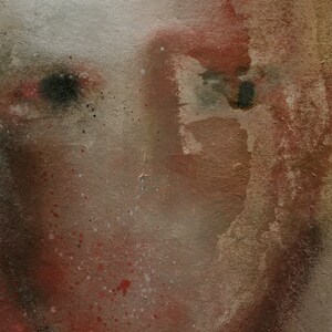 A detail of a modern watercolor-effect female portrait in maroon, beige, brown and grey. The woven texture is spray painted, two thick paper layers are torn to shape, with rough edges. A vague nose, scratched off the paint, hair line and black eyes.