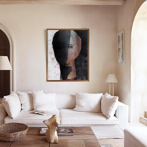 May include: A framed abstract painting of a face with a black and white color scheme. The face is partially obscured by a black shape, and the background is a light pink with a floral pattern.