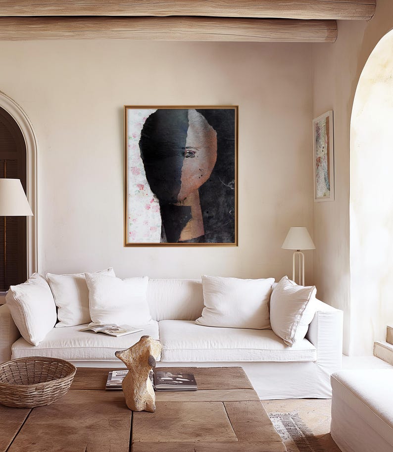 May include: A framed abstract painting of a face with a black and white color scheme. The face is partially obscured by a black shape, and the background is a light pink with a floral pattern.