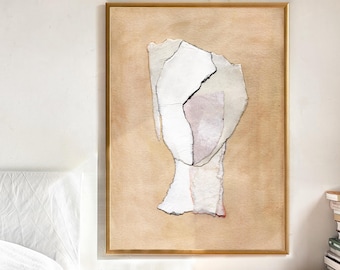 May include: Abstract art print in a gold frame. The artwork features torn paper pieces in white, light pink, and beige, arranged against a beige background. A black line accentuates a tear in the paper. The framed art is displayed on a wooden surface.