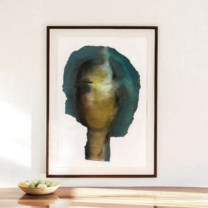 A wall art decor with a dark framed high quality Giclee print of a moody decadent abstract female portrait in shades of petrol blue, golden, yellow and black. The torn-to-shape laid paper piece has rough edges. The grainy texture is spray painted.