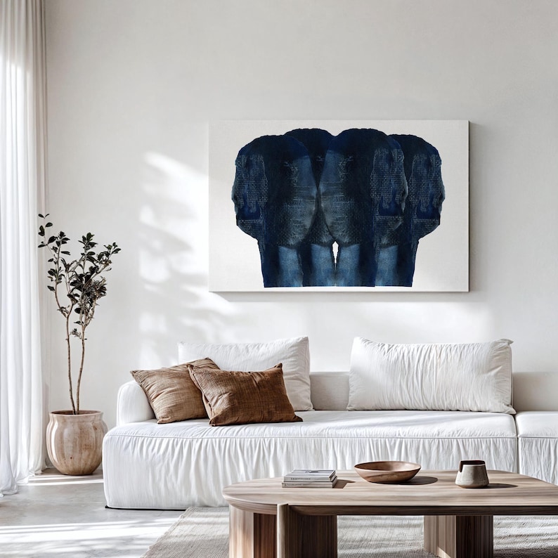 Puede incluir: Un sof&aacute; blanco con cojines marrones se encuentra frente a una pared blanca con una pintura abstracta azul colgada encima. Una planta en maceta est&aacute; en el lado izquierdo de la imagen.