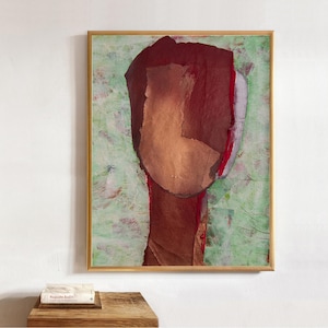 Pode incluir: Uma pintura abstrata emoldurada apresentando uma figura central em tons de bordô escuro e cobre sobre um fundo verde claro texturizado. A obra exibe pinceladas em camadas e blocos de cores, dentro de uma moldura fina de cor dourada.