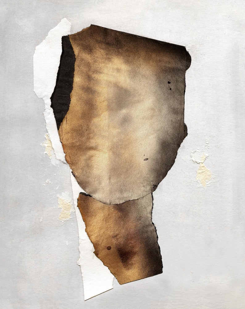 May include: A piece of paper with torn edges, revealing a layer of brown paper underneath. The brown paper has a faded, aged look and is stained with brown and black spots.