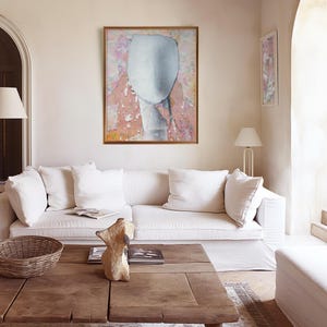 A soft collored gallery wall art with a framed high quality Giclee art print of a tender female abstract portrait in pastel tones of salmon and off white on a floral background with violet and orange. It is made of torn paper pieces, rich in texture.