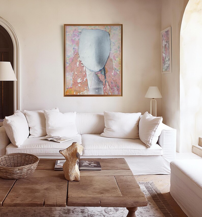 A soft collored gallery wall art with a framed high quality Giclee art print of a tender female abstract portrait in pastel tones of salmon and off white on a floral background with violet and orange. It is made of torn paper pieces, rich in texture.