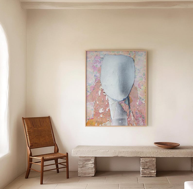 A warm collored wall decor with a framed high quality archival art print of a tender female abstract portrait in pastel tones of salmon and off white on a floral background with violet and orange. It is made of torn paper pieces, rich in texture.