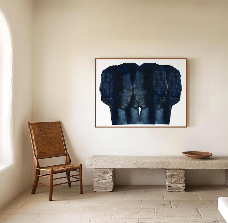 Puede incluir: Una pintura abstracta azul de tres figuras en un marco blanco colgada en una pared beige sobre un banco de hormig&oacute;n. Una silla de madera est&aacute; en primer plano.
