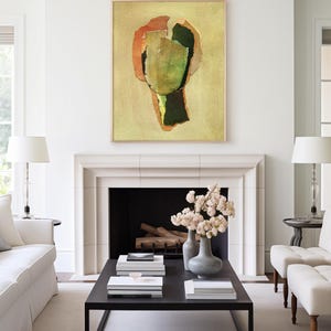 May include: Abstract art piece in a wooden frame, featuring a collage of green, orange, and brown shapes on a yellow background. The artwork hangs above a fireplace in a bright, modern living room setting.