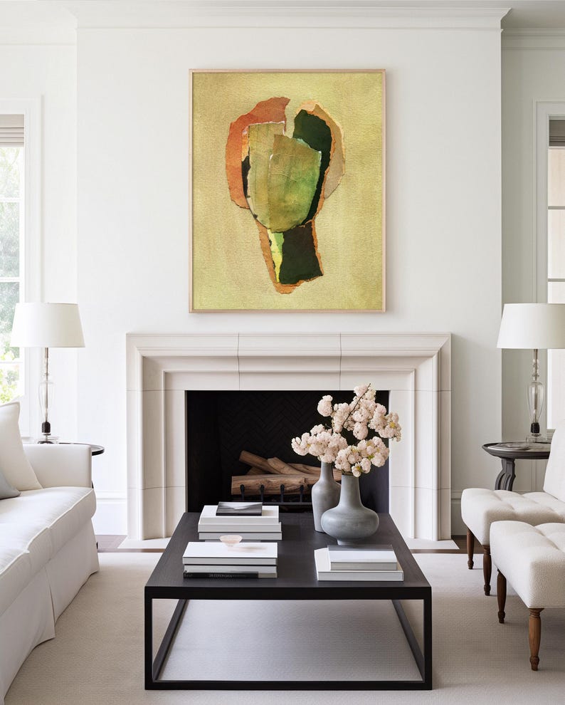May include: Abstract art piece in a wooden frame, featuring a collage of green, orange, and brown shapes on a yellow background. The artwork hangs above a fireplace in a bright, modern living room setting.