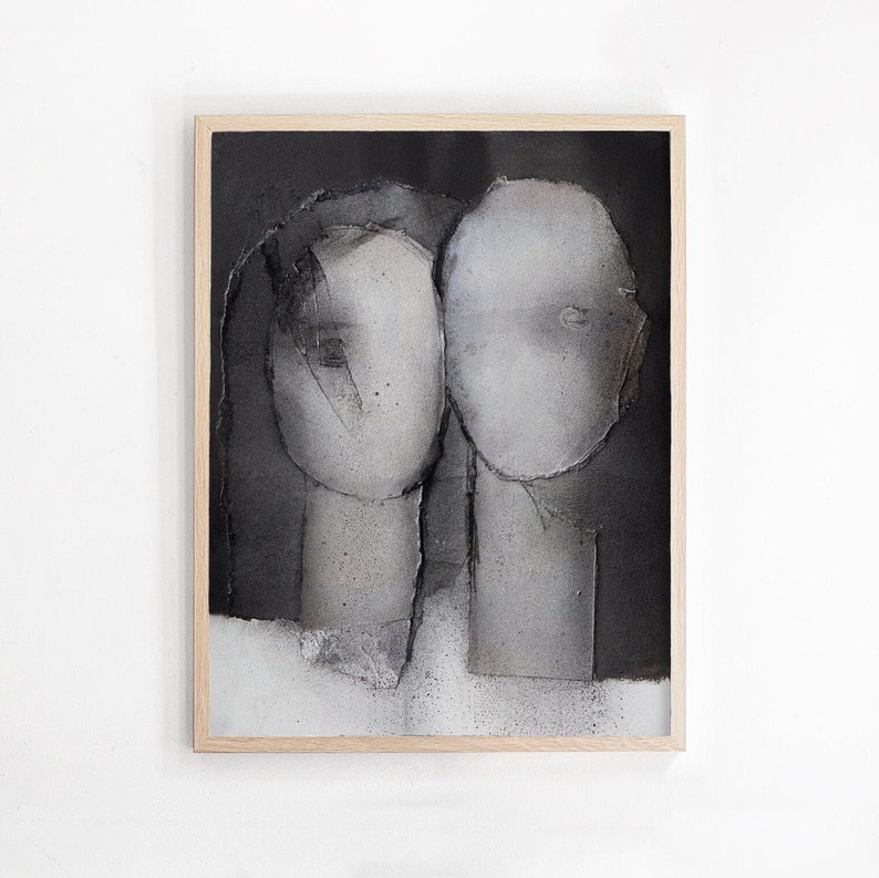 A light wood framed art print of a noir abstract portrait of a grayscale love couple on spray-painted black-and-white background. The heads have torn paper layers with exposed grungy edges and two roughly outlined eyes. The texture is grainy.