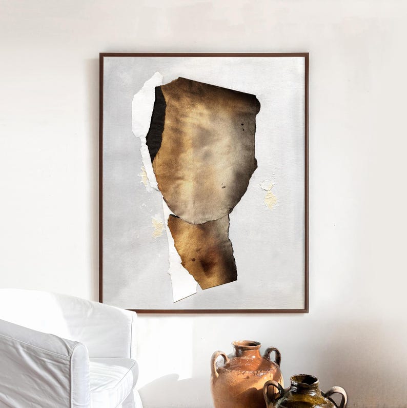 May include: Abstract art print featuring a torn piece of paper with brown and beige tones against a white background. The paper is framed in a dark brown wood frame.