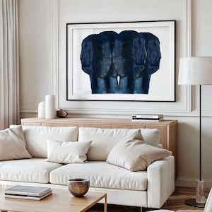 Puede incluir: Un sof&aacute; blanco con dos almohadas blancas y una pintura abstracta azul colgada encima. La pintura est&aacute; en un marco negro y est&aacute; en una pared blanca.