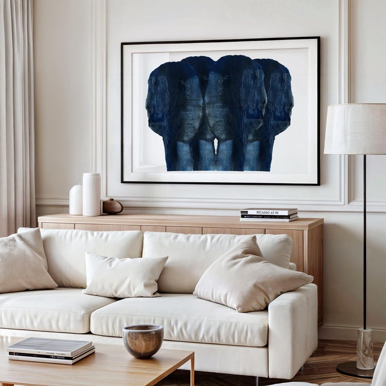 Puede incluir: Un sof&aacute; blanco con dos almohadas blancas y una pintura abstracta azul colgada encima. La pintura est&aacute; en un marco negro y est&aacute; en una pared blanca.