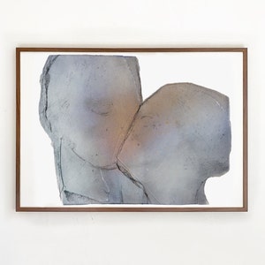 A dark wood framed high quality art print of a romantic abstract portrait of a love couple kiss in greige, dovetail and silver grey on white. The torn paper layers have grungy edges and a mural feel. The kiss is accented with a hue of a golden glow.